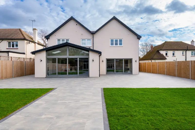 Rear of a detached house with a glazed gable extension, new patio and lawn